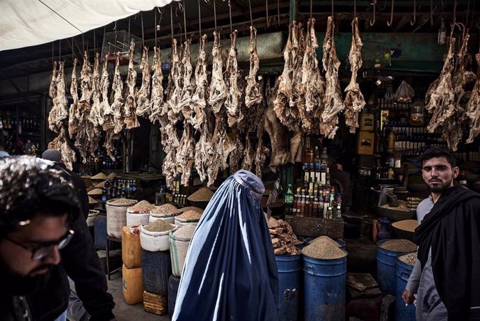 Archivo - Una mujer con burka compra en un mercado en Afganistán