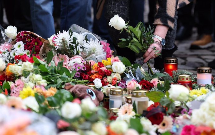 21 December 2024, Saxony-Anhalt, Magdeburg: A woman lays flowers at the official memorial site at St. John's Church in Magdeburg. The previous evening, a driver rammed into a group of people at Magdeburg's Christmas market. Several people were killed and 