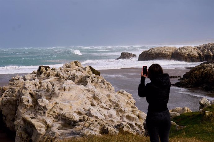 Archivo - Una persona fotografía las olas rompiendoen Santander