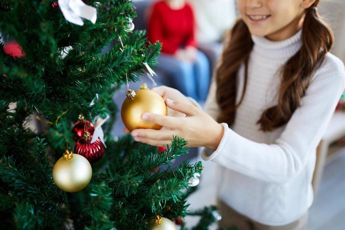 Archivo - Niña adornando el árbol de Navidad.