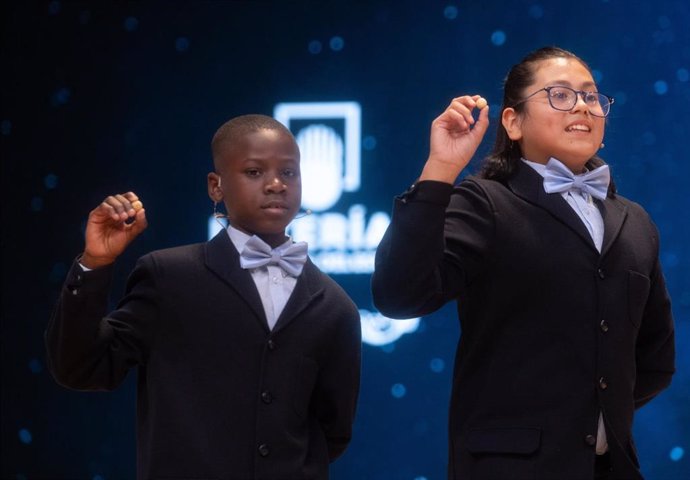 Agustín Nicanor Bikoro Mangue (i) y Rodrigo Román Benítez(d), cantan un quinto premio durante la celebración del Sorteo Extraordinario de la Lotería de Navidad 2024, en el Teatro Real, a 22 de diciembre de 2024, en Madrid (España). 