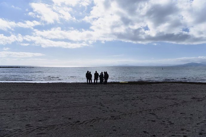 Archivo - Guardias civiles frente a un cadáver de un migrante en la orilla de una playa de Ceuta, en una imagen de archivo.