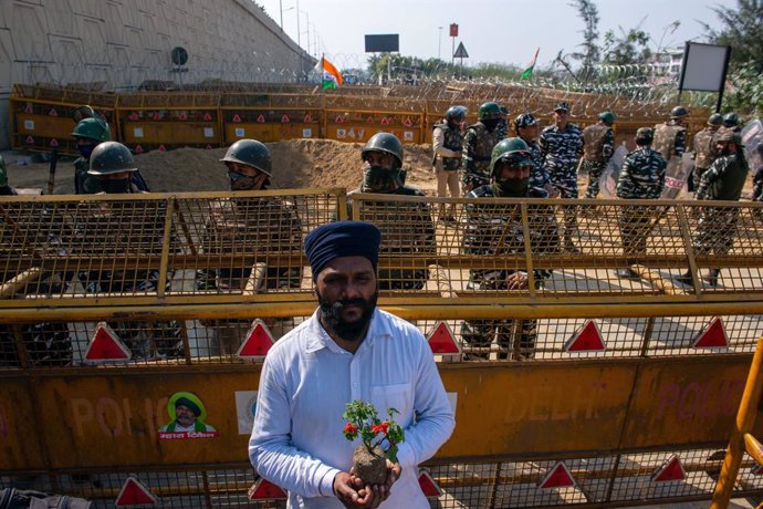 Archivo - February 6, 2021, Ghaziabad, Uttar Pradesh, India: A Sikh farmer holding a flower plant standing before barricades with police personnel on a highway at Ghazipur border, during the demonstration. Farmers called for roads to be blocked across Ind