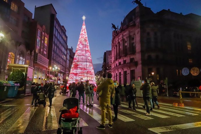 Archivo - Varias personas observan un árbol de Navidad 