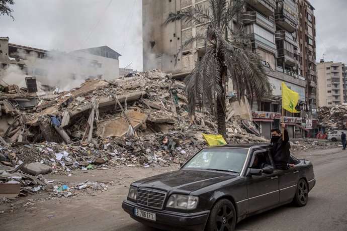 November 27, 2024, Beirut, Lebanon: Hezbollah supporters drive past a still smoking building in Dahiyeh, greater Beirut, following the beginning of a ceasefire. A US-brokered ceasefire between Israel and Hezbollah came into effect at 4am local time.