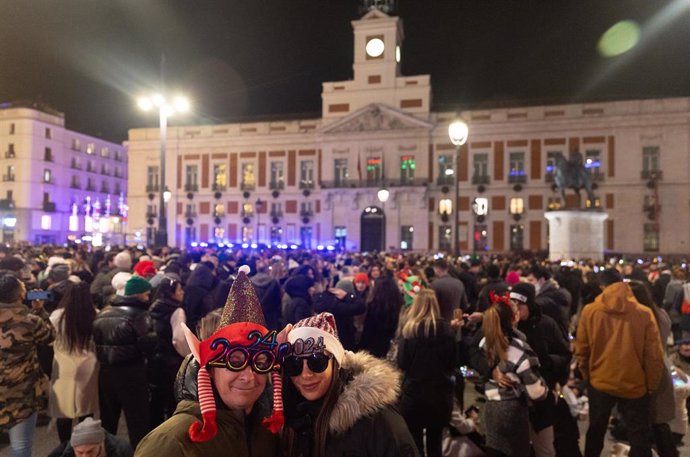 Archivo - Dos personas disfrazadas se hacen una foto con el reloj de fondo, antes de las campanadas de Nochevieja 2023, en la Puerta del Sol 