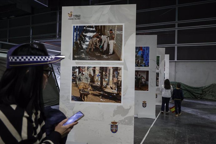 Una mujer observa durante la inauguración de Expojove 2024 y en el espacio de este certamen dedicado al Ejército fotografías de la actuación de los militares en poblaciones afectadas por la dana.