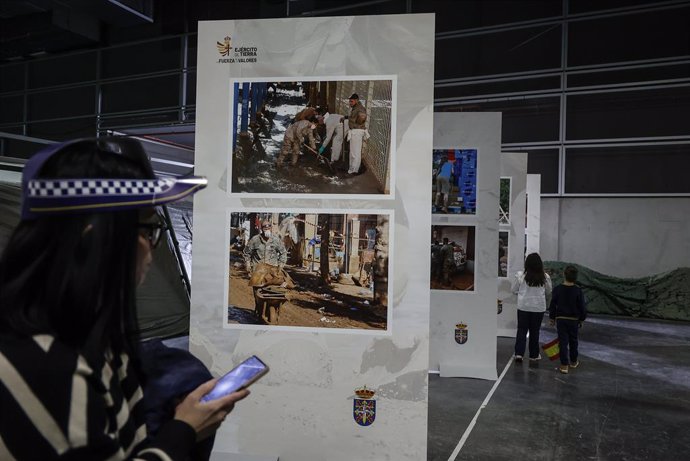 Una dona observa durant la inauguració d'Expojove 2024 i en l'espai d'este certamen dedicat a l'Exèrcit fotografies de l'actuació dels militars en poblacions afectades per la dana.