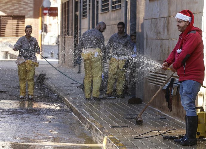 Un home amb un casquet de Papà Noel ajuda a netejar el carrer en un municipi afectat per la dana