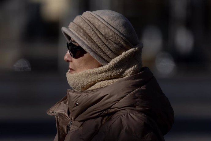 Una mujer abrigada con bufanda y gorro pasea por la ciudad, a 9 de diciembre de 2024, en Madrid (España).  