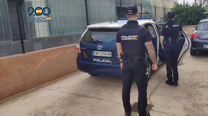 Agentes de la Policía Nacional frente a un coche patrulla.