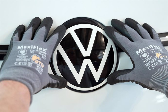 Archivo - FILED - 08 June 2021, Saxony, Dresden: A Volkswagen employee places the VW logo in a VW ID.3 during a press tour of Volkswagen's Transparent Factory. 