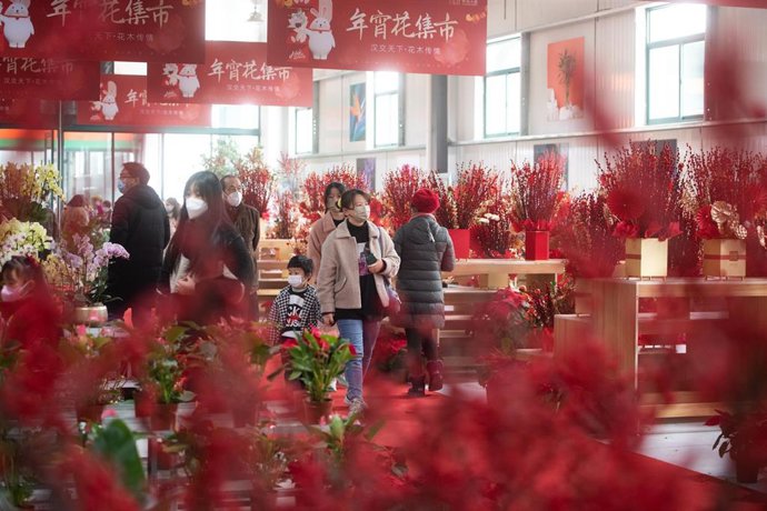 Archivo - Personas con mascarilla en un mercado de Wuhan, China