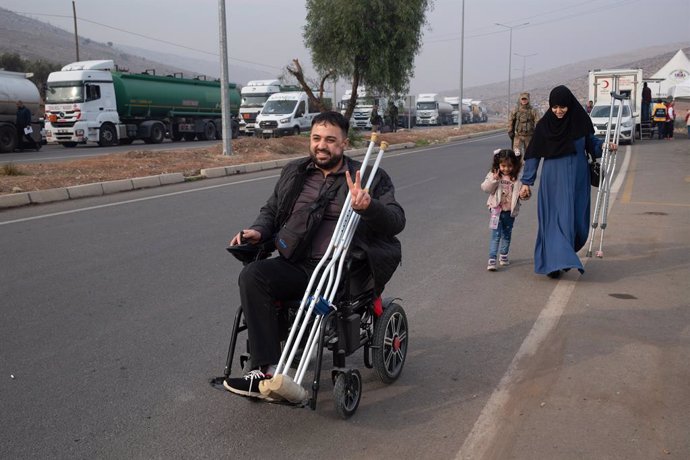 11 December 2024, Turkey, Hatay: A Syrian refugee in a wheelchair makes a victory sign on his way to the border. Islamist-led opposition forces announced that they had captured the Syrian capital Damascus, allowed President Bashar al-Assad to flee and end