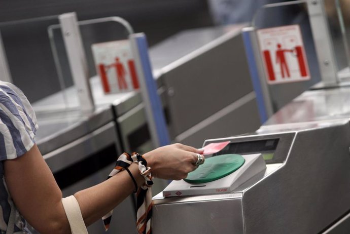 Archivo - Una mujer pasa su billete en el torno del Metro Plaza de España, en Madrid (España), a 6 de julio de 2020.