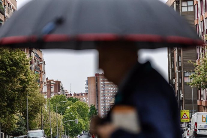 Archivo - Una persona camina bajo la lluvia, en una foto de archivo. 