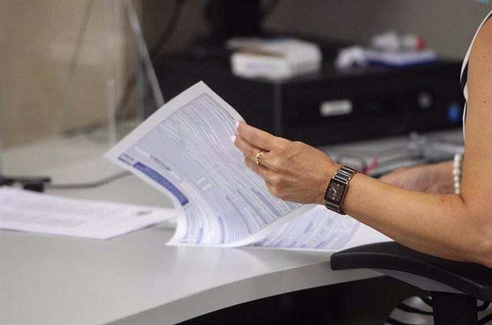 Archivo - Una empleada hojea varias hojas en su puesto de trabajo de la Oficina de Hacienda de la Calle de Guzmán el Bueno, a 27 de julio de 2021, en Madrid, (España). El Gobierno prevé aprobar este martes en Consejo de Ministros una Oferta de Empleo Públ