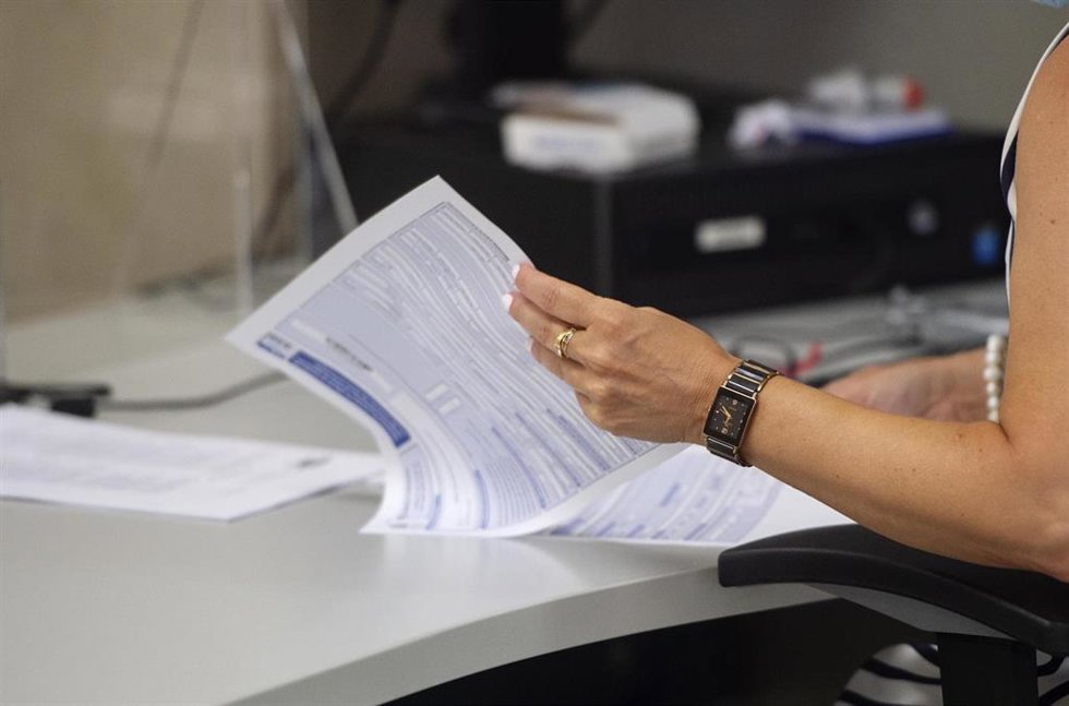 Archivo - Una empleada hojea varias hojas en su puesto de trabajo de la Oficina de Hacienda de la Calle de Guzmán el Bueno, a 27 de julio de 2021, en Madrid, (España). El Gobierno prevé aprobar este martes en Consejo de Ministros una Oferta de Empleo Pú