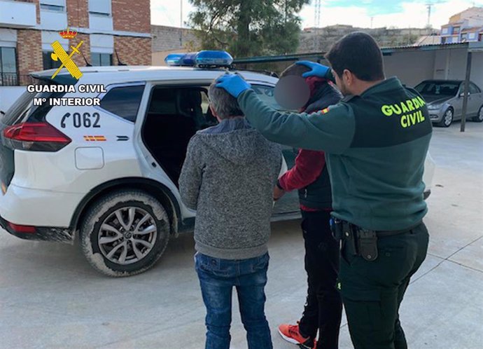 Un agente de la Guardia Civil custodia a dos de los detenidos por el atraco a un local de apuestas en Bullas (Murcia)