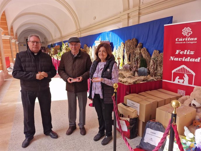 La presidenta de la UCAM, María Dolores García, entrega al director de Cáritas Diócesis de Cartagena, José Antonio Planes, los vales correspondientes a la recaudación del concierto solidario de Navidad