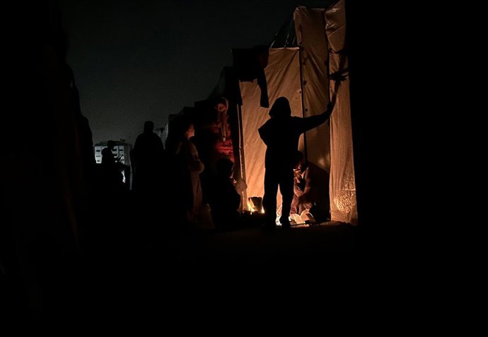 December 24, 2024, Nuseirat, Gaza Strip, Palestinian Territory: A Palestinian family tries to protect themselves from the cold weather by lighting a fire in a tent, at Nusaierat Refugee Camp, located in the central part of the Gaza Strip, on December 27, 