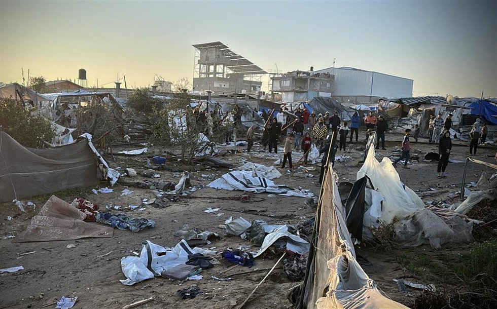 Palestinians look around at the site of a previous Israeli army strike in the Al-Mawasi area, a designated humanitarian zone, in the central Gaza Strip. 