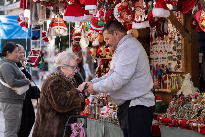 Varias personas observan el ambiente navideño en la Fira de Santa Llúcia de Barcelona