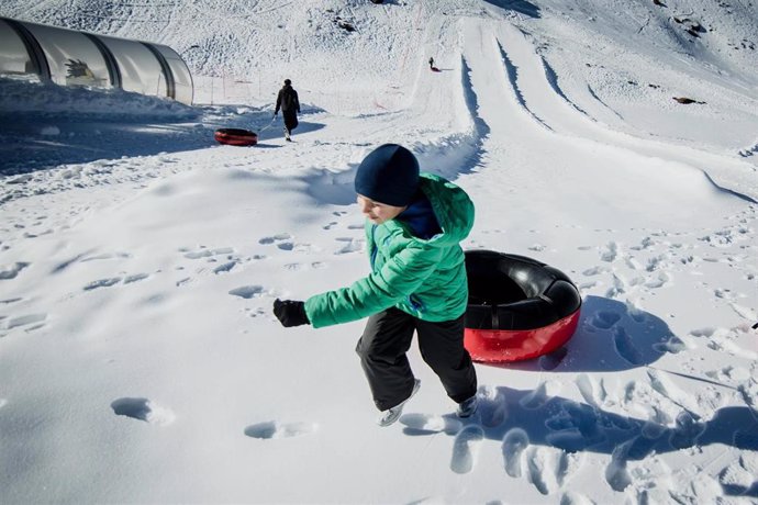 Archivo - Un niño se dispone a lanzarse con un flotador en la zona de Borreguiles de la Estación de Sierra Nevada, en imagen de archivo