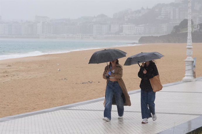 Archivo - Dos mujeres caminan con paraguas en la playa de Ondarreta, a 14 de octubre de 2023, en San Sebastián, Guipúzcoa, País Vasco (España). Según la Agencia Estatal de Meteorología (AEMET), el tiempo de hoy en la capital de Guipúzcoa viene marcado por