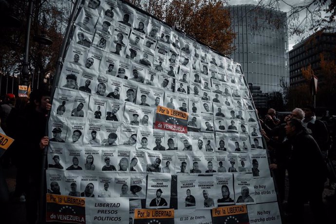 Archivo - Un cartel de protesta con fotografías durante una manifestación de venezolanos en Madrid