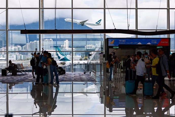 Archivo - A Cathy Pacific aircraft takes off as travellers wait for departure at Hong Kong International Airport. 