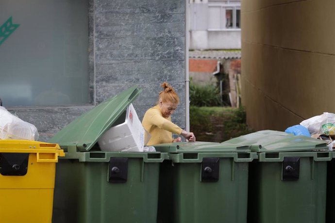 Archivo - Una mujer deposita una bolsa de basura al lado de contenedores de basura, en una imagen de archivo