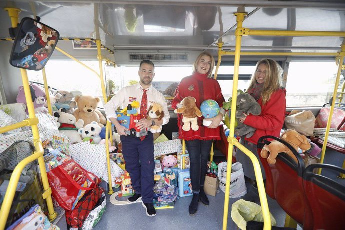 La concejal de Servicios Sociales del Ayuntamiento de Córdoba, Eva Contador, y el personal de la empresa City Sightseeing en el autobús turístico con juguetes para los niños de familias en exclusión.