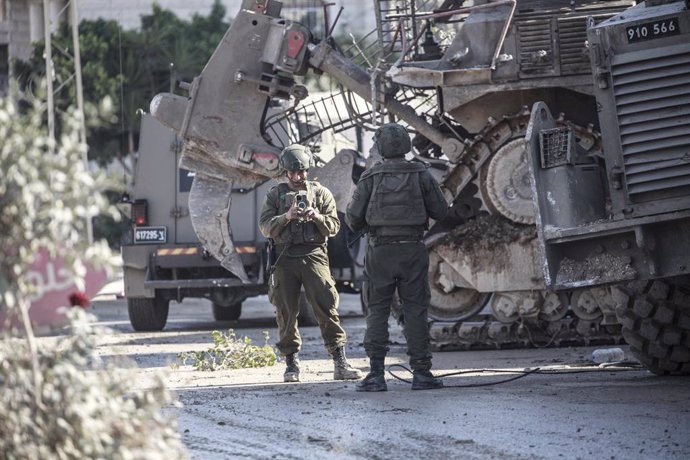 December 25, 2024, Tulkarm, West Bank, Palestine: An Israeli soldier uses his mobile phone to take pictures of his colleague during an Israeli raid on Tulkarm refugee camp, east of Tulkarm city in the West Bank. The raid killed seven Palestinians, arreste