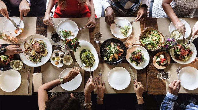 Archivo - Concepto de gente comiendo en una mesa con todo tipo de comida. Veganismo, vegetarianismo u omnívorismo