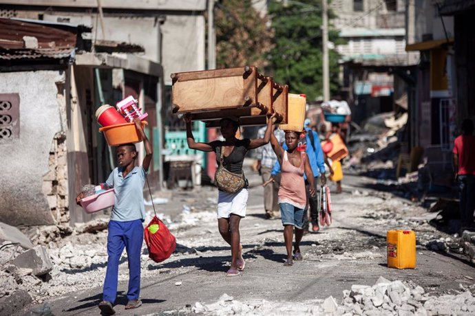 Un grupo de personas portan enseres en una calle de Puerto Príncipe, Haití