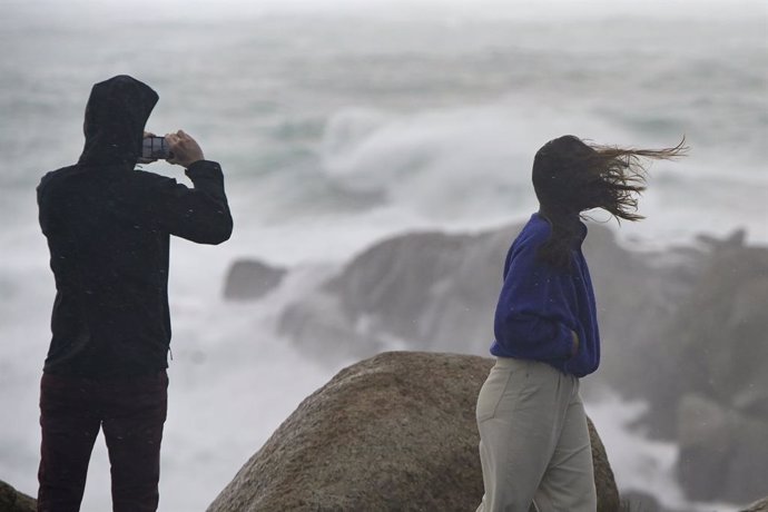 Archivo - Una persona fotografía el mar embravecido, mientras el viento mueve la melena a su acompañante, a 4 de noviembre de 2023, en A Coruña, Galicia (España). 