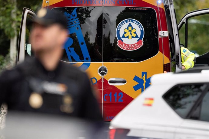 Archivo - Una ambulancia junto a un agente de la Policía Nacional en Madrid.