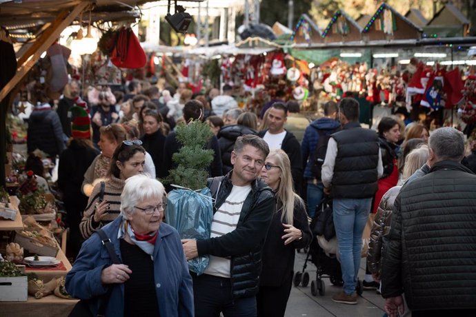 Archivo - Varias personas realizan sus compras navideñas en el mercado navideño de Santa Llúcia de Barcelona.