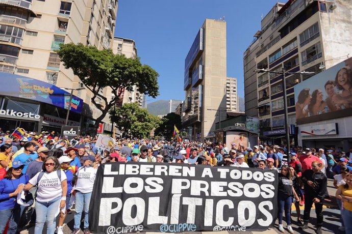 09 January 2025, Venezuela, Caracas: Opponents of the government hold a banner reading "Release all political prisoners" during a demonstration called by the opposition one day before authoritarian President Nicolas Maduro was sworn in for another term in