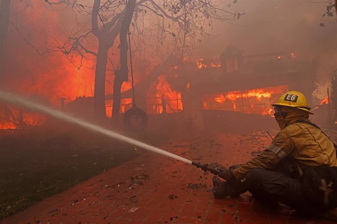 Bomberos tratando de sofocar el incendio que asola Los Ángeles.