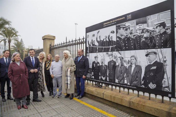 La presidenta de la Autoridad Portuaria de la Bahía de Cádiz, Teófila Martínez, y el fotoperiodista gaditano, Joaquín Hernández Conde 'Kiki', junto a una de las imágenes de la exposición instalada en la verja del muelle gaditano.