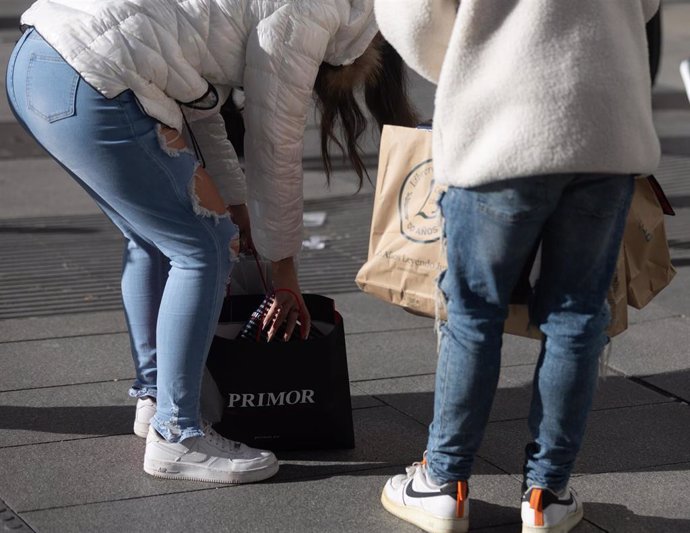 Archivo - Dos personas llevan bolsas con regalos