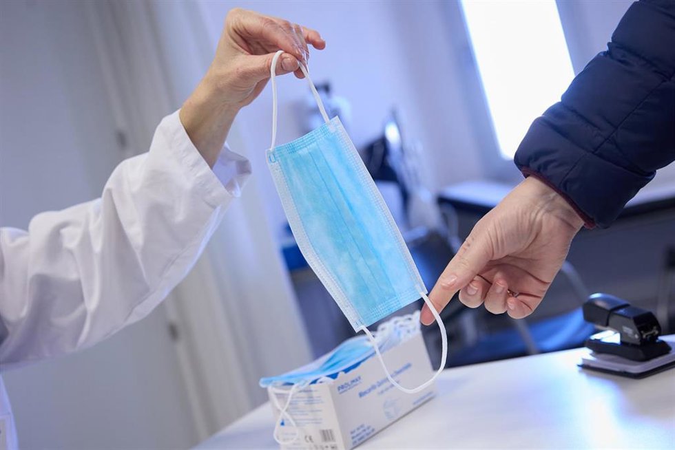 Archivo - Una sanitaria ofrece una mascarilla a un paciente