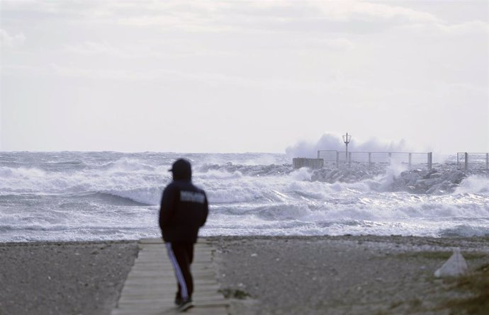 Archivo - Varias personas en la playa de la Malagueta donde el temporal con vientos de 70 km/h y el litoral malagueño registra olas de tres metros. Imagen de archivo. 