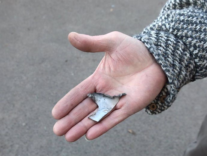 January 1, 2025, Kyiv, Ukraine: KYIV, UKRAINE - JANUARY 1, 2025 - A woman holds a fragment outside a residential building in the Sviatoshynskyi district damaged by a Russian drone strike, Kyiv, capital of Ukraine.