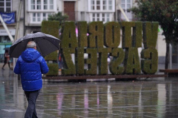 Archivo - Un ciudadano camina bajo la lluvia en Vitoria