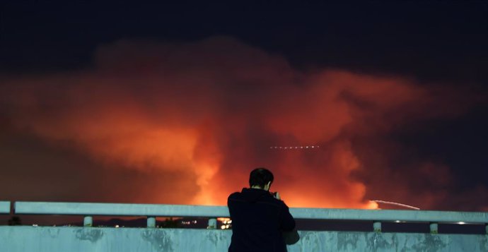 People take photos of the Palisades fire explodes looking like a volcano in the Santa Monica mountains into the San Fernando Valley causing evacuations Friday, Van Nuys CA. Jan 10, 2025.