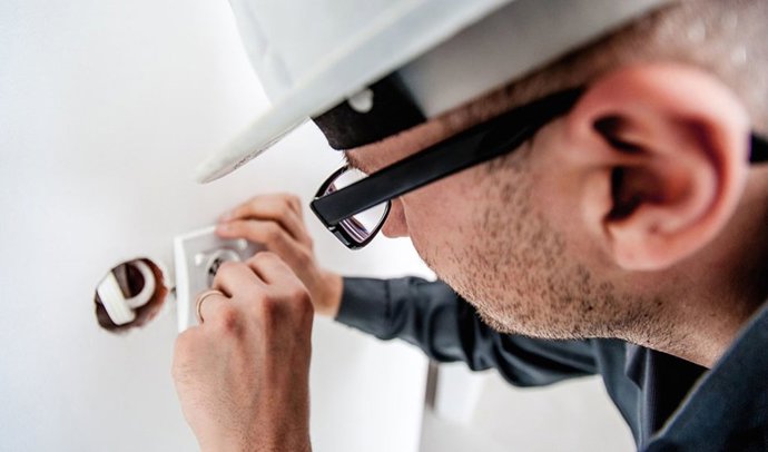 Archivo - Un electricista completa una instalación eléctrica en un domicilio.