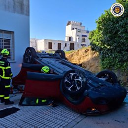 Efectivos de bomberos actuando en el coche siniestrado en un aparcamiento de Conil.